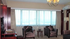 A hotel room with a large window, two armchairs, a small table, and a desk with a chair. - Rongshui Miaoshan International Hotel (Liuzhou)