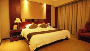 A hotel room with a large bed, a nightstand with a lamp, a red chair, and a window with curtains. - Rongshui Miaoshan International Hotel (Liuzhou)