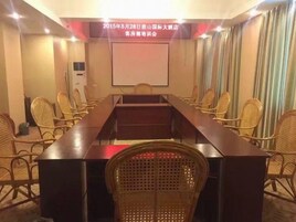 A conference room with a long table, chairs, a projector screen, and a wall-mounted air conditioning unit.