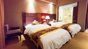A hotel room with two beds, a chair, a nightstand with a lamp, and a bathroom visible through a glass door. - Rongshui Miaoshan International Hotel (Rongshui)