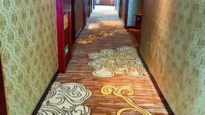 A hallway with patterned carpet and walls, leading to a room with a bed. - Rongshui Miaoshan International Hotel (Rongshui)