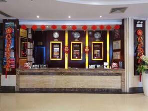 Un mostrador de recepción con diplomas enmarcados, un reloj y adornos rojos.