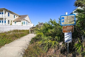 A pathway leading to a beach area with signs indicating beach access and turtle protection.