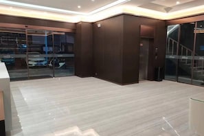 A modern interior with a glass door entrance, a wooden floor, and a dark wall. - Yujia Boutique Hotel (Taihu County)