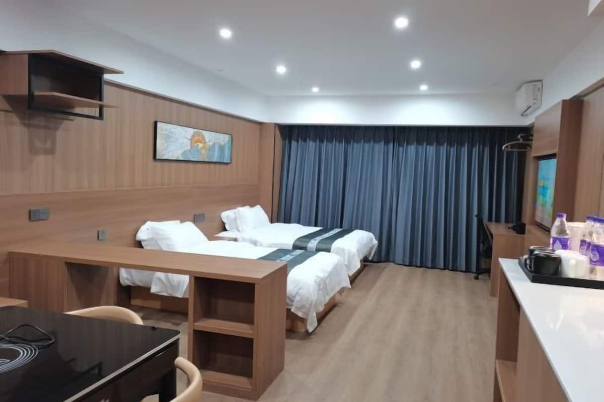 Una habitación de hotel con dos camas, un escritorio, una silla, un televisor y un cuadro en la pared.