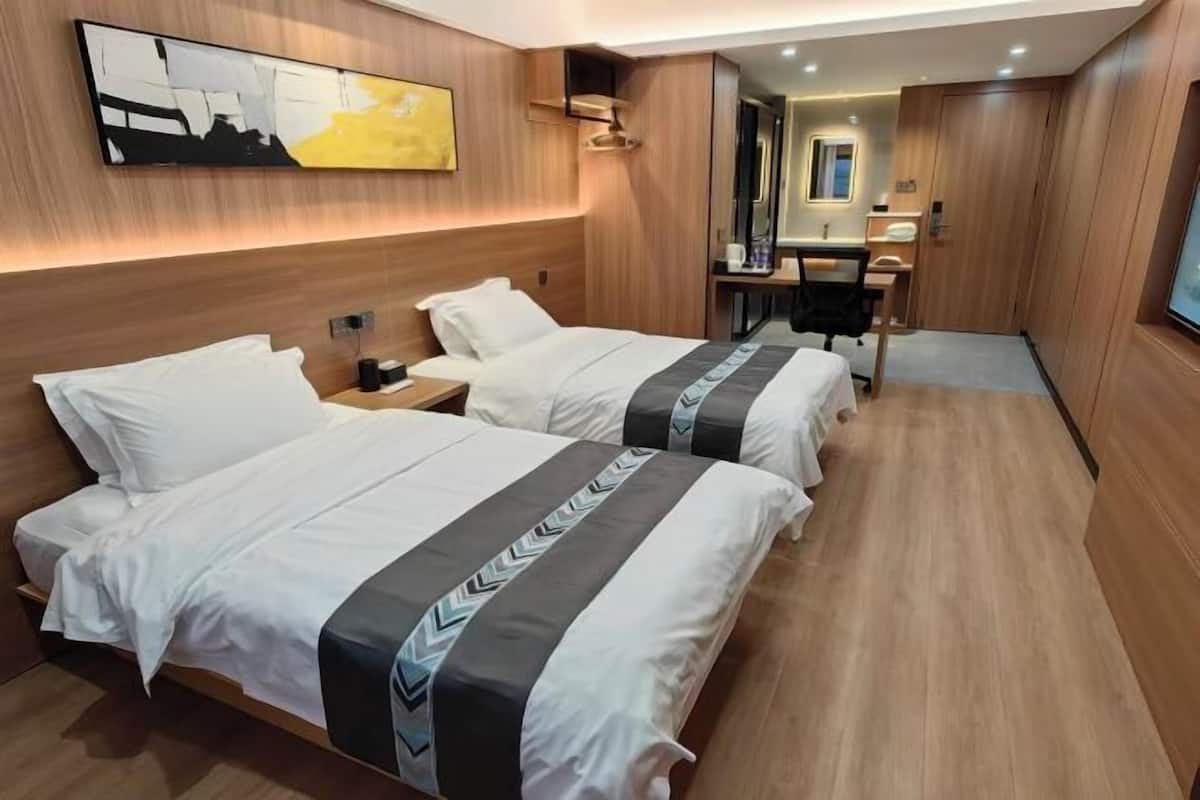 Habitación de hotel con dos camas, un escritorio, un espejo y un cuadro en la pared.