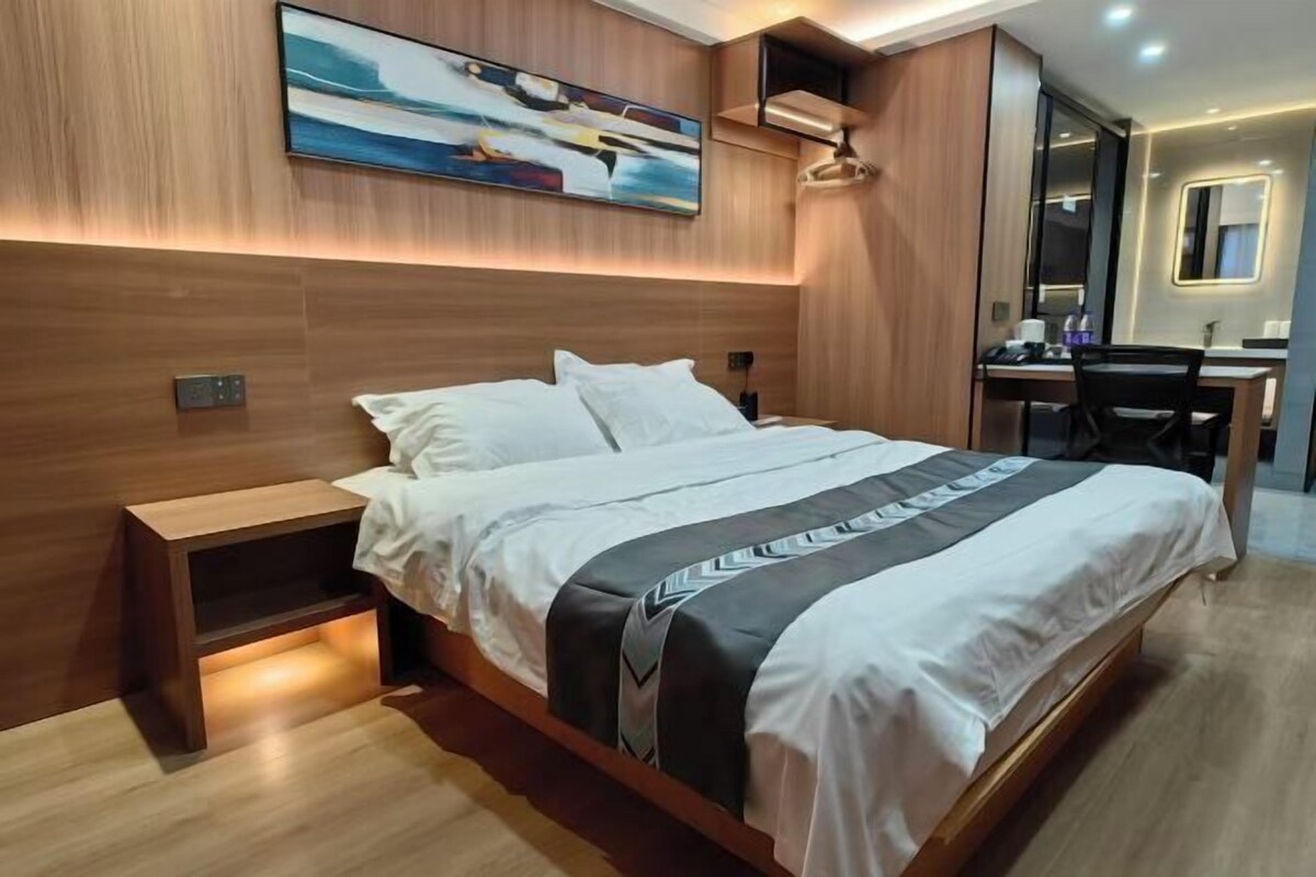 Quarto de hotel moderno com uma cama grande, uma escrivaninha e um espelho.