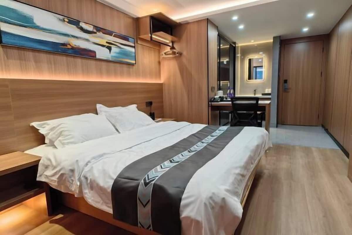 Una habitación de hotel moderna con una cama grande, un escritorio y un espejo.