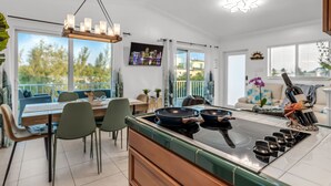 A modern kitchen with a central island, dining area with chairs, and a view of the outdoors. - Luxury 4B/3B, Private Canal, Kayaks, 13 ft Hot Tub, 4 H Mini-Golf & Pedal Boat. (Tavernier)