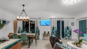 A modern dining area with a wooden table, green chairs, and a chandelier. - Luxury 4B/3B, Private Canal, Kayaks, 13 ft Hot Tub, 4 H Mini-Golf & Pedal Boat. (Tavernier)