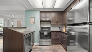 Una cocina moderna con electrodomésticos de acero inoxidable, armarios de madera y un salpicadero de azulejos.
