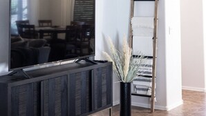 A modern living room with a flat-screen TV, a black entertainment unit, and a wooden ladder. - The Gilbert Haven - comfortable, stylish w/ pool (Gilbert)
