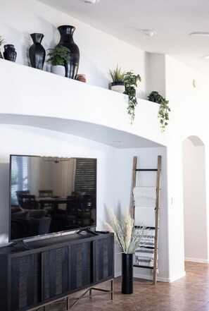 Relax in this stylish living room with a flat-screen TV, decorative vases, and lush plants.