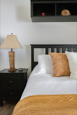 Cozy retreat with a neatly made bed, nightstand, and shelf.