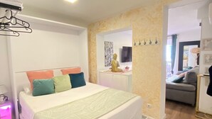 A bedroom with a bed, a bedside table, a wall-mounted TV, and a mirror. - Check-in 24horas madrid (Madrid)