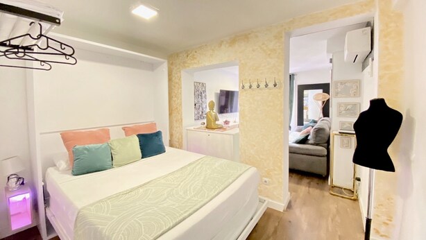 A hotel room with a bed, a wardrobe, a mirror, a mannequin, and a wall-mounted air conditioner. - Check-in 24horas madrid (Madrid)