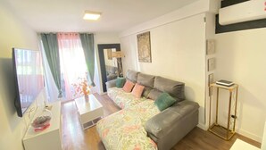 A living room with a sofa, a coffee table, a TV, and a small table with a book. - Check-in 24horas madrid (Madrid)