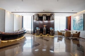 A modern hotel lobby with a reception desk, seating area, and a large abstract painting on the wall. - Dongfang Yijing Hotel (Jinyun)