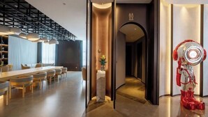 Un moderno vestíbulo de hotel con un mostrador de recepción alargado, un separador de vidrio y una escultura roja única.