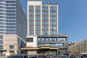 Un edificio de varios pisos con un diseño arquitectónico moderno, que destaca una entrada con toldo amarillo y señalización.