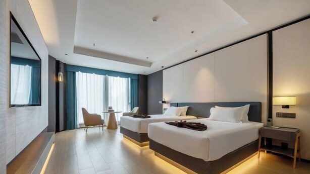 Una habitación de hotel moderna con dos camas, una mesita y una silla.