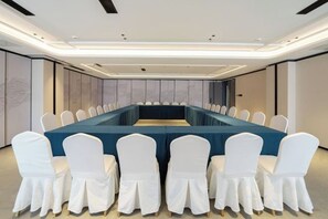 A conference room with a long table, white chairs, and a modern ceiling design. - Dongfang Yijing Hotel (Jinyun)