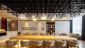 Un comedor moderno con una mesa larga y varias sillas, iluminación colgante y una estantería al fondo.
