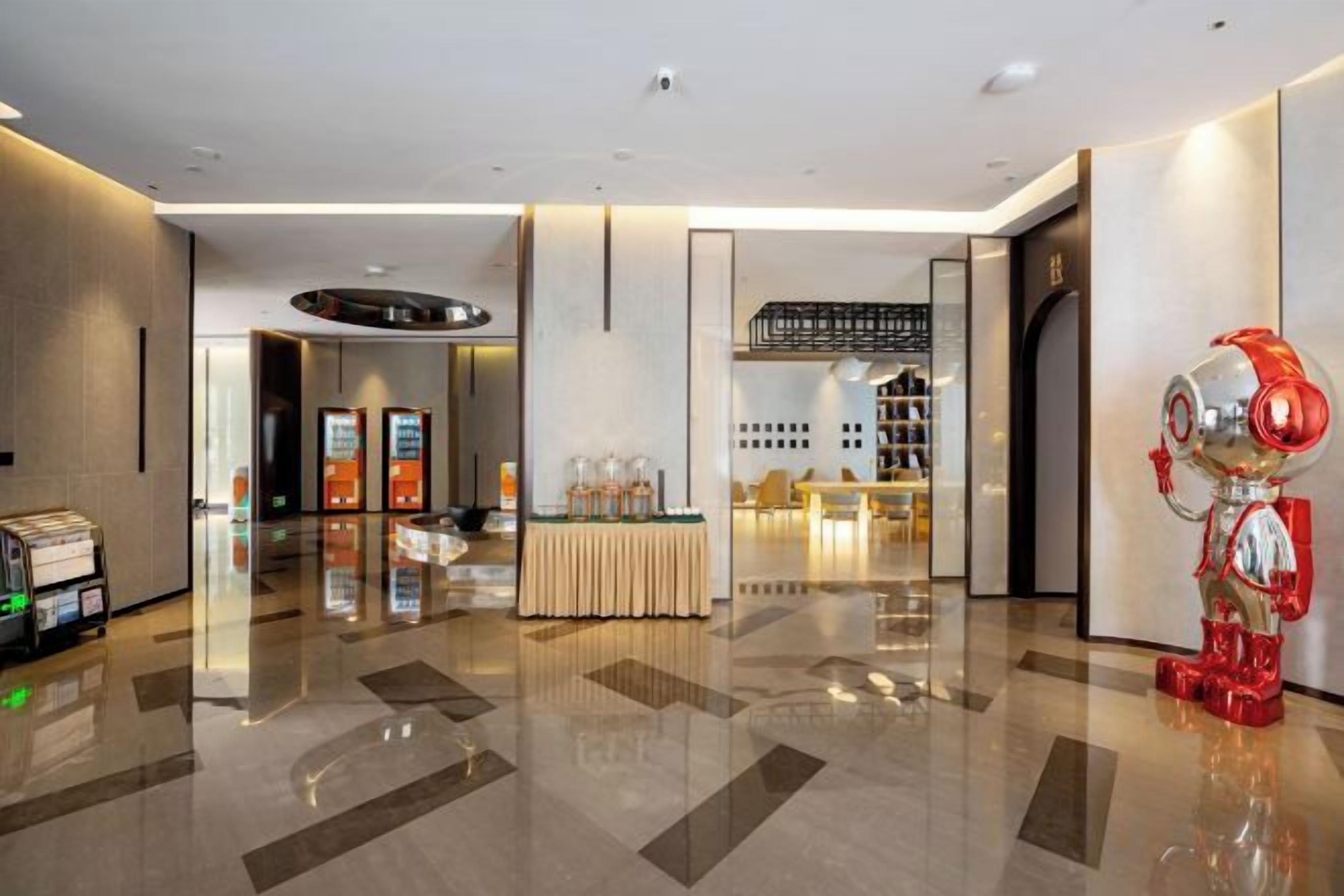 A modern hotel lobby with a reception desk, a vending machine, and a decorative robot statue.