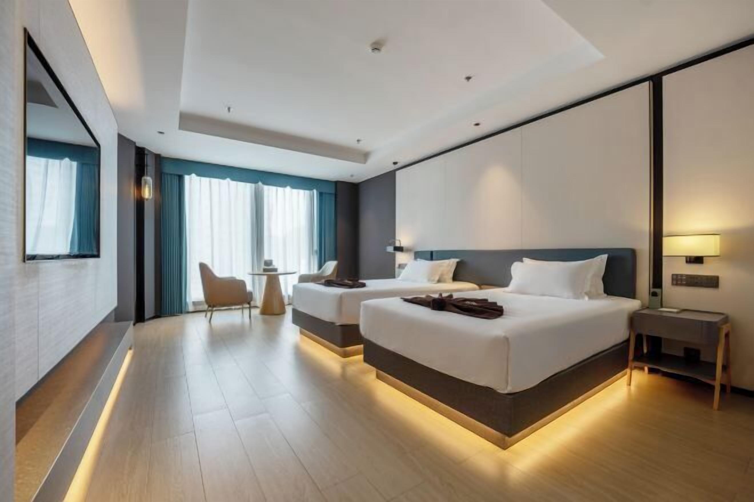 Una habitación de hotel moderna con dos camas, un escritorio y una silla.