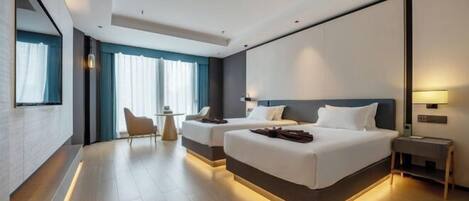 A modern hotel room with two beds, a desk, and a chair.