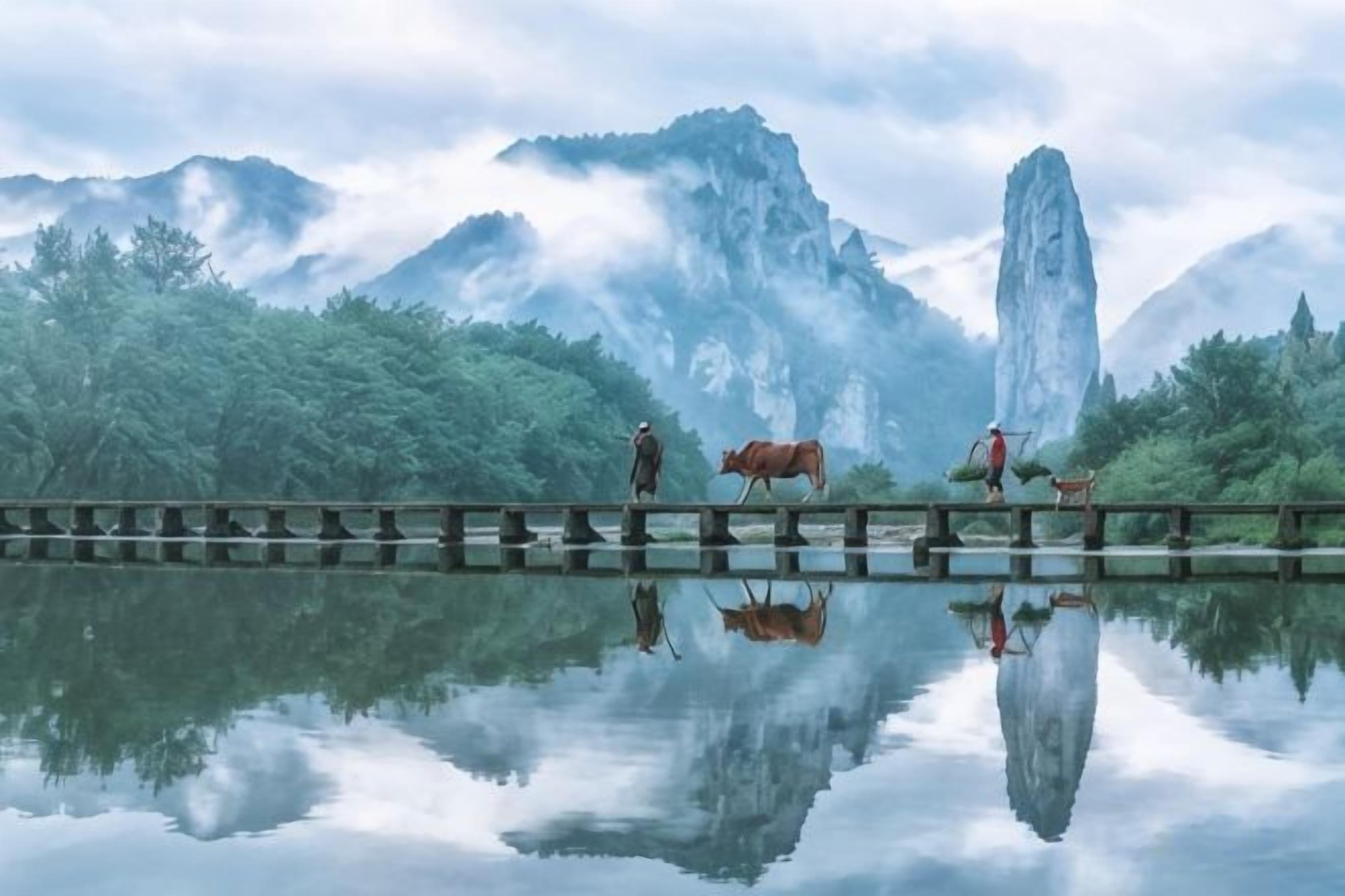 A reflective water surface with a wooden bridge, a person, and a horse in a mountainous landscape.