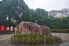 A stone monument with inscriptions, surrounded by a fence and greenery. - Dongfang Yijing Hotel (Jinyun)
