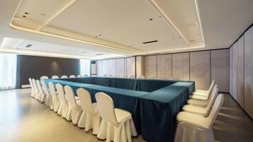 A conference room with a long table, white chairs, and a blue tablecloth.