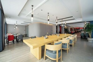 A modern conference room with a long wooden table, multiple chairs, and pendant lighting. - Dongfang Yijing Hotel (Jinyun)