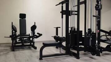 A gym with various exercise equipment, including a bench press, squat rack, and weight benches.