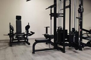 A gym with various exercise equipment, including a bench press, squat rack, and weight benches.