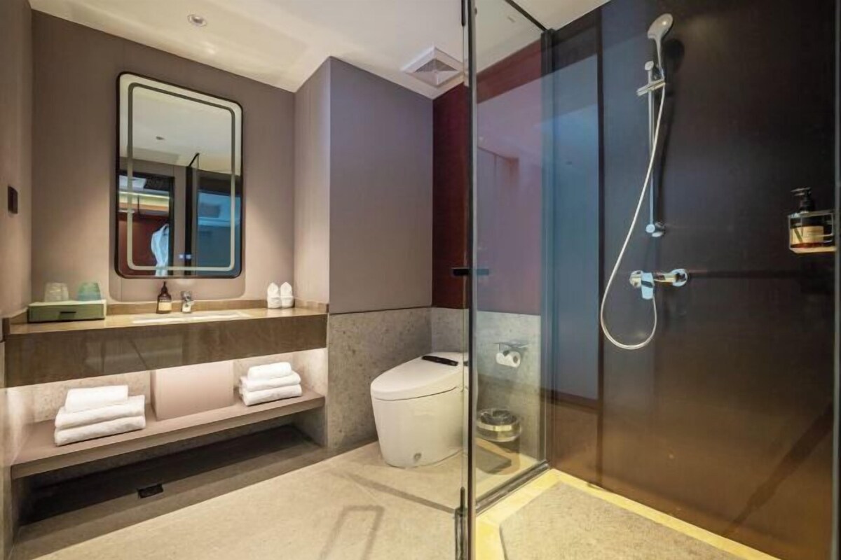A modern bathroom with a glass-enclosed shower, a vanity with a mirror, and a toilet.
