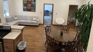A modern living room with a grey sectional sofa, a dining table with wooden chairs, a white chair, a ceiling fan, and a large abstract painting. - 4 bedrooms 3 bath, Tranquil Home, Master suite & Jet tub, Mins from Hot Springs (Thermopolis)