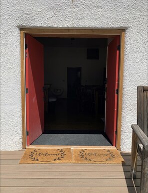 A wooden door with a doormat and a small rug leading to an interior space with a chair and a table. - 4 bedrooms 3 bath, Tranquil Home, Master suite & Jet tub, Mins from Hot Springs (Thermopolis)