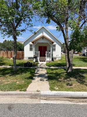 A single-story house with a red door and a porch, surrounded by trees and a wooden fence. - 4 bedrooms 3 bath, Tranquil Home, Master suite & Jet tub, Mins from Hot Springs (Thermopolis)