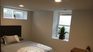 A bedroom with a bed, a window with a plant, and a small cabinet. - 4 bedrooms 3 bath, Tranquil Home, Master suite & Jet tub, Mins from Hot Springs (Thermopolis)