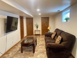 A living room with a sofa, a coffee table, a television, and a door. - 4 bedrooms 3 bath, Tranquil Home, Master suite & Jet tub, Mins from Hot Springs (Thermopolis)