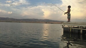 A person fishing at a lakeside dock with mountains in the background. - 4 bedrooms 3 bath, Tranquil Home, Master suite & Jet tub, Mins from Hot Springs (Thermopolis)