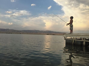 A person fishing at a lakeside dock with mountains in the background. - 4 bedrooms 3 bath, Tranquil Home, Master suite & Jet tub, Mins from Hot Springs (Thermopolis)