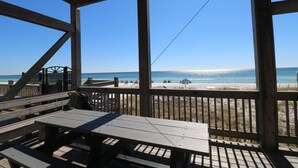 A wooden deck with picnic tables overlooking a beach.