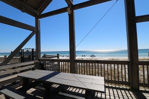 Une terrasse en bois avec des tables de pique-nique donnant sur une plage.