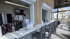 A bar area with a counter, chairs, and a view of the sea.