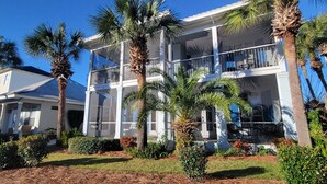 A multi-story building with balconies, surrounded by palm trees and well-maintained landscaping.