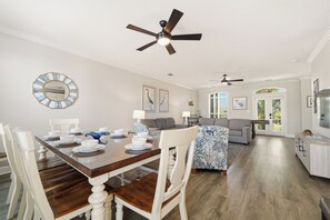 A dining area with a wooden table, white chairs, and a ceiling fan.