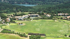 Ein Golfplatz mit Clubhaus, umgeben von Wohngebäuden und dichtem Wald.